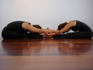 Paschimottanasana or seated forward bend pose with partner